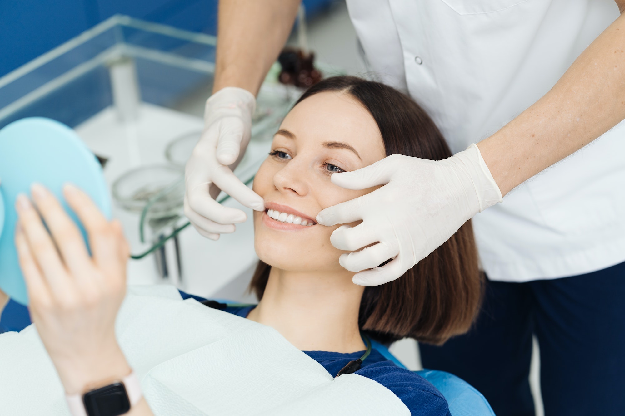 Dentist hands and happy patient looking in mirror after treatment